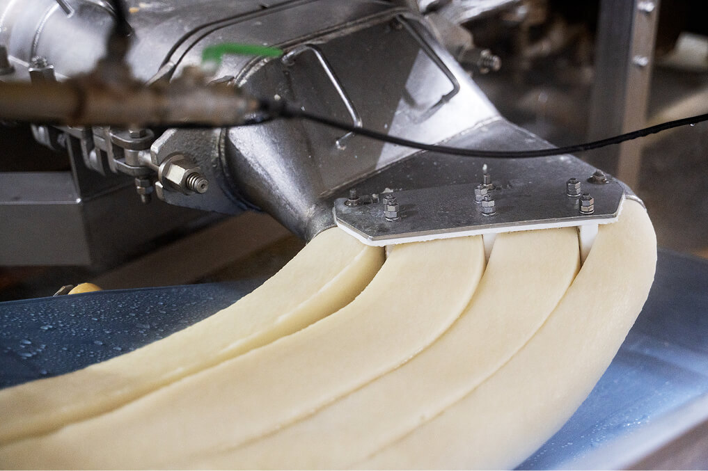 蒸しあがった生地が４列になって機械から出てくる写真