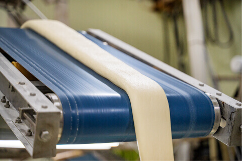 蒸し上がった1本の生地がローラーの上を移動していく写真