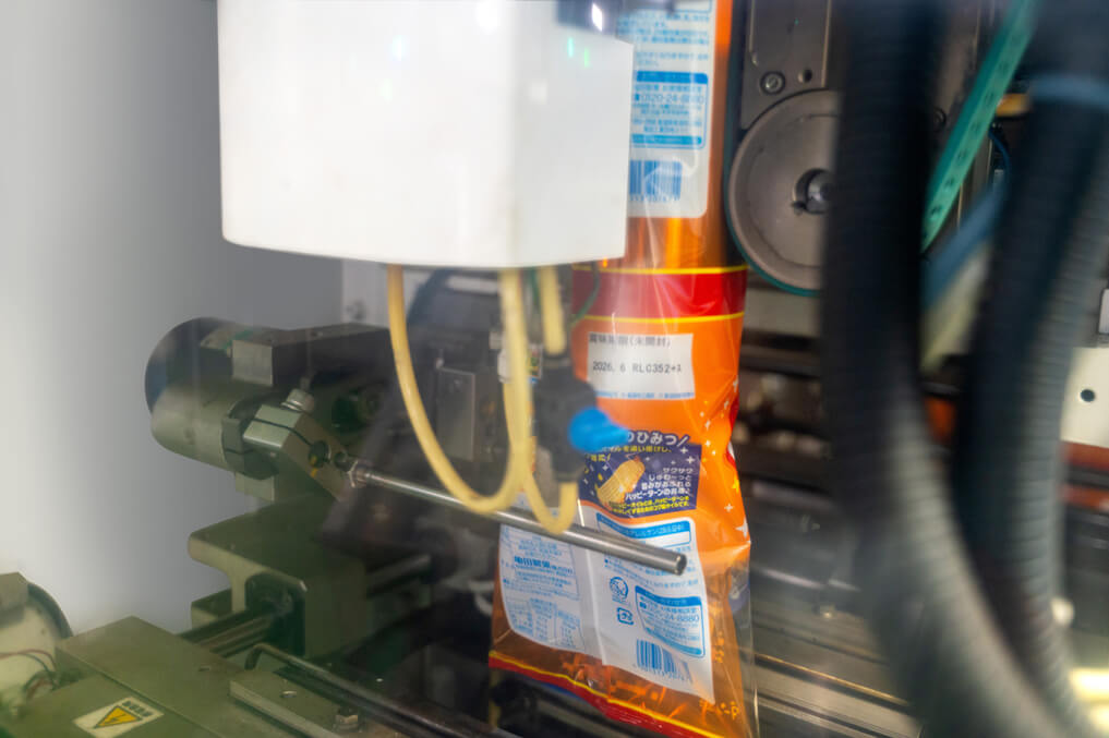 機械によって大袋にハッピーターンが封入される様子